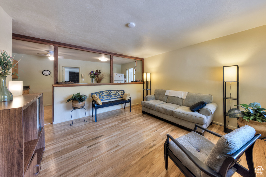 Living room with light wood-style floors, a wall mounted AC, and baseboards