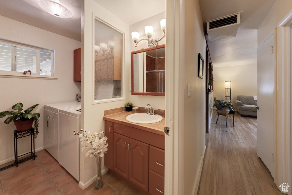 Bathroom featuring washer and clothes dryer, vanity, and wood finished floors
