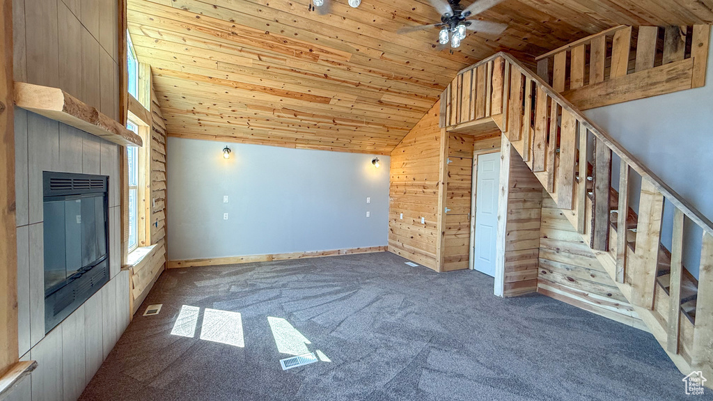 Unfurnished living room with wooden ceiling, lofted ceiling, wood walls, ceiling fan, and carpet floors