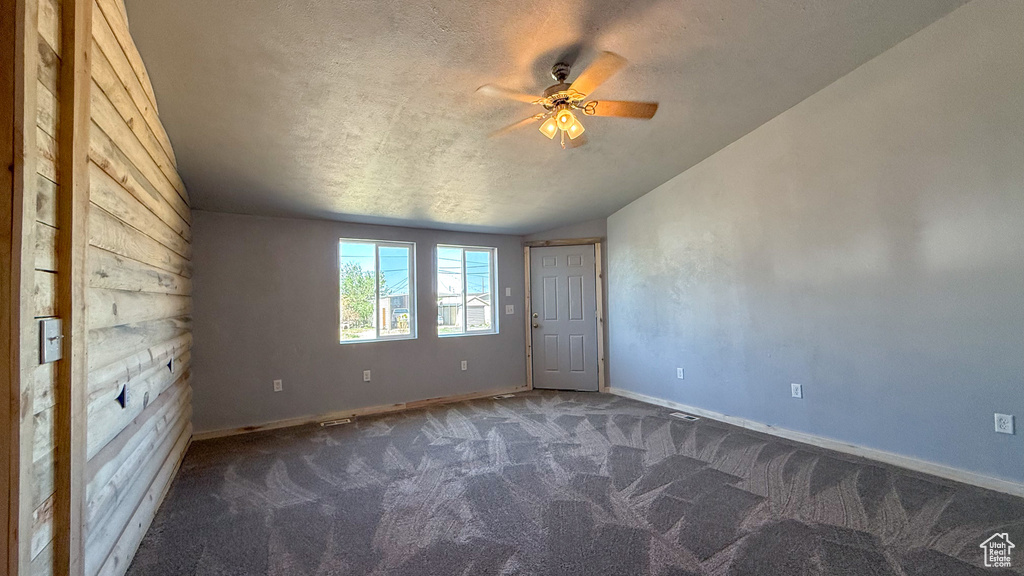 Carpeted empty room with a ceiling fan, a textured ceiling, baseboards, and vaulted ceiling