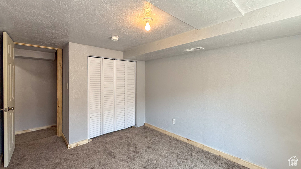 Unfurnished bedroom featuring a closet, baseboards, carpet, and a textured ceiling