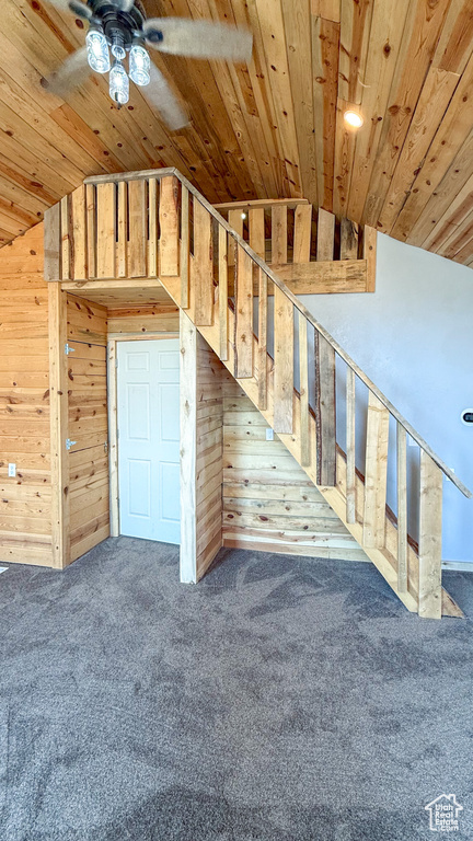 Staircase featuring wooden walls, wood ceiling, carpet flooring, ceiling fan, and lofted ceiling