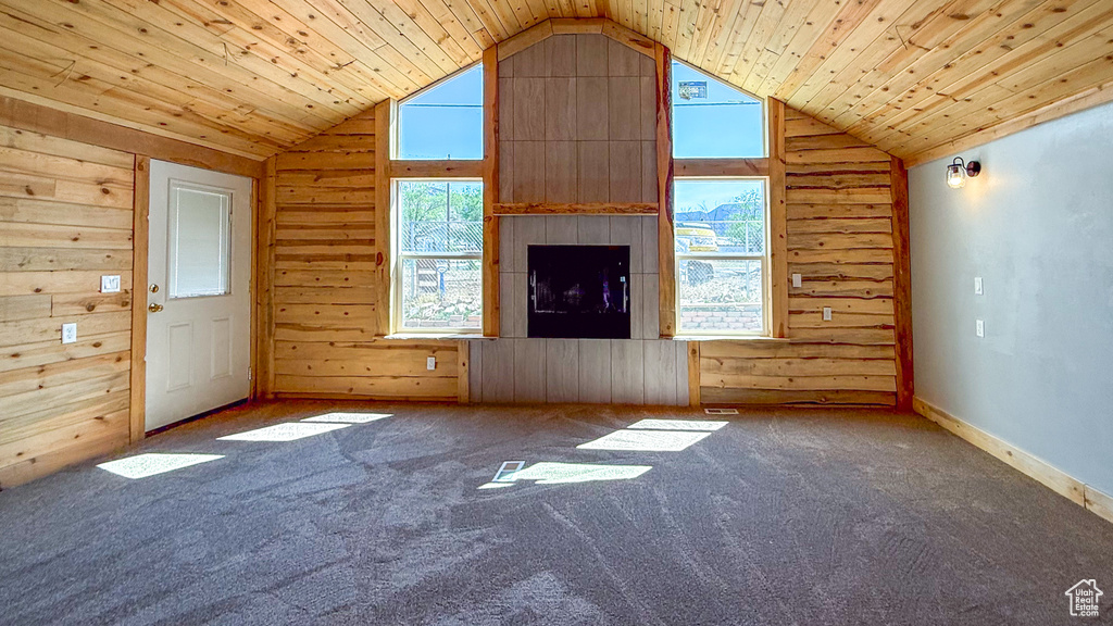 Unfurnished living room with lofted ceiling, wooden walls, carpet, and wood ceiling