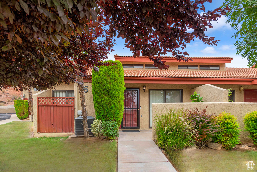 View of front of property with a fenced front yard, central AC unit, stucco siding, and a tiled roof