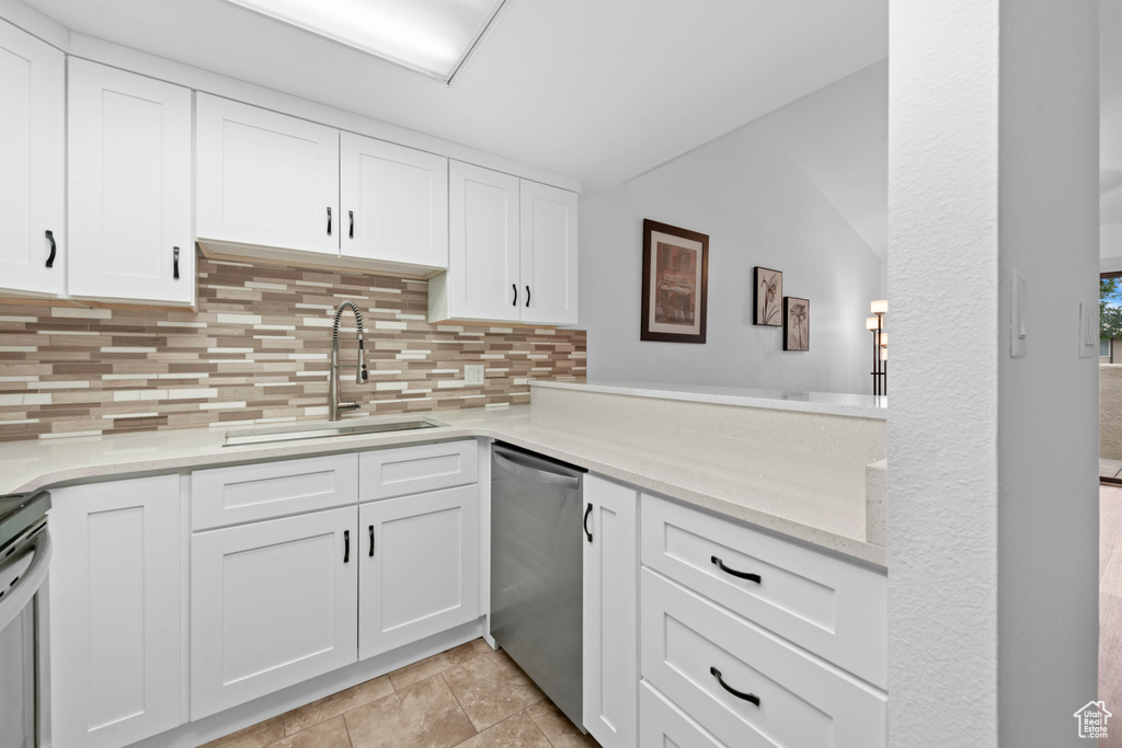 Kitchen with a sink, dishwasher, tasteful backsplash, vaulted ceiling, and white cabinets