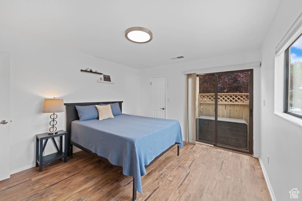 Bedroom featuring access to outside, wood finished floors, and baseboards
