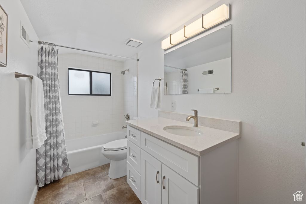 Full bathroom with vanity, shower / bath combo, and toilet