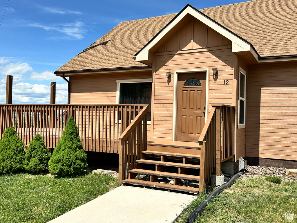 Entrance to property with roof with shingles and a deck