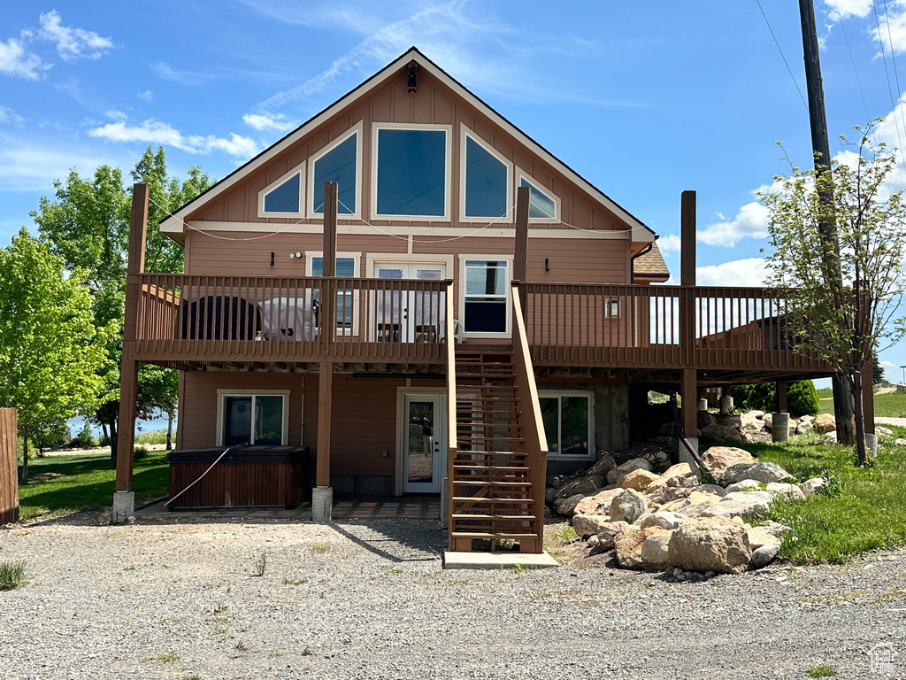 Rear view of property featuring a hot tub, a wooden deck, stairs, and board and batten siding