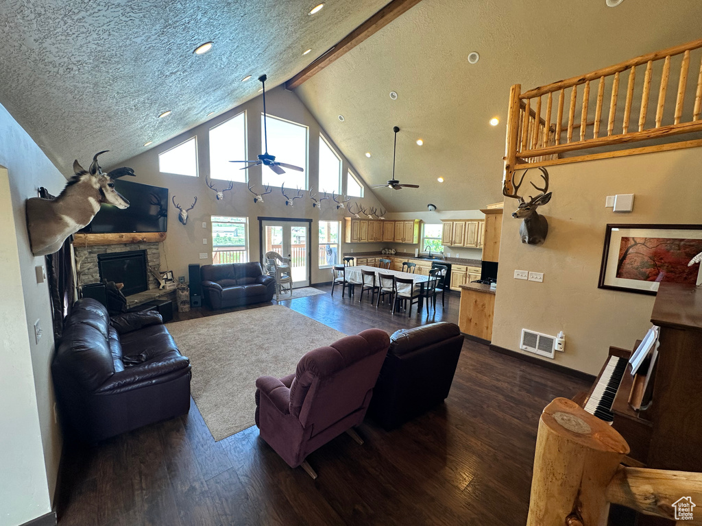 Living room with dark wood-type flooring, a ceiling fan, a fireplace, recessed lighting, and high vaulted ceiling