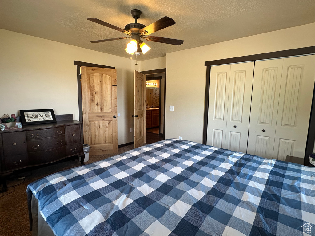 Carpeted bedroom featuring a closet, a textured ceiling, and ceiling fan