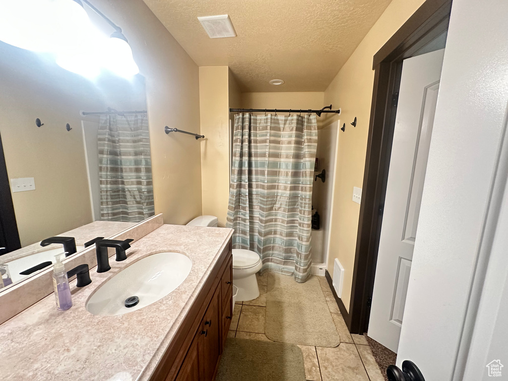 Bathroom featuring toilet, vanity, a textured ceiling, and a shower with curtain