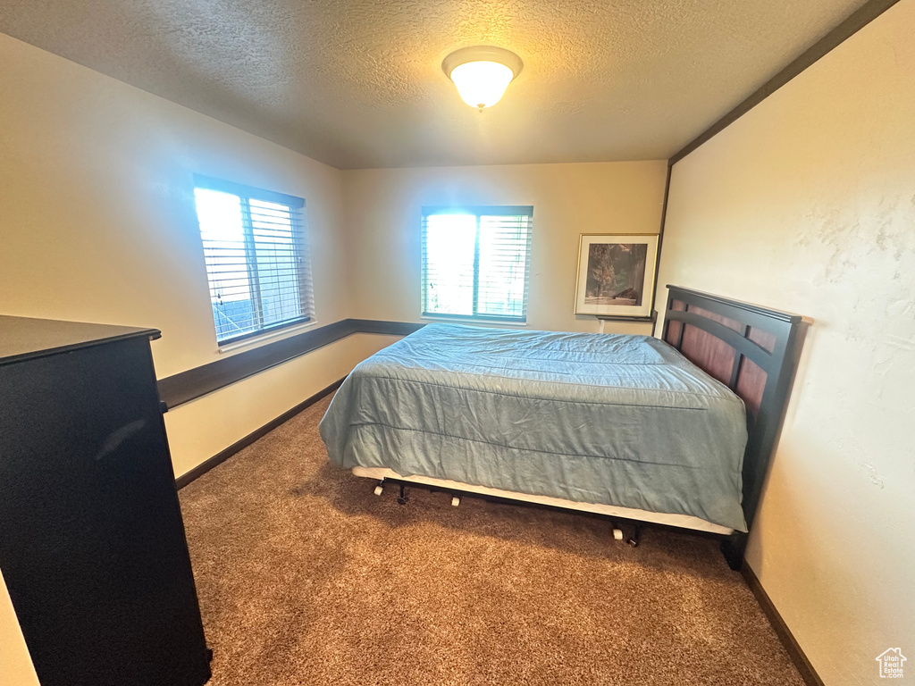 Bedroom with a textured ceiling, carpet floors, and baseboards
