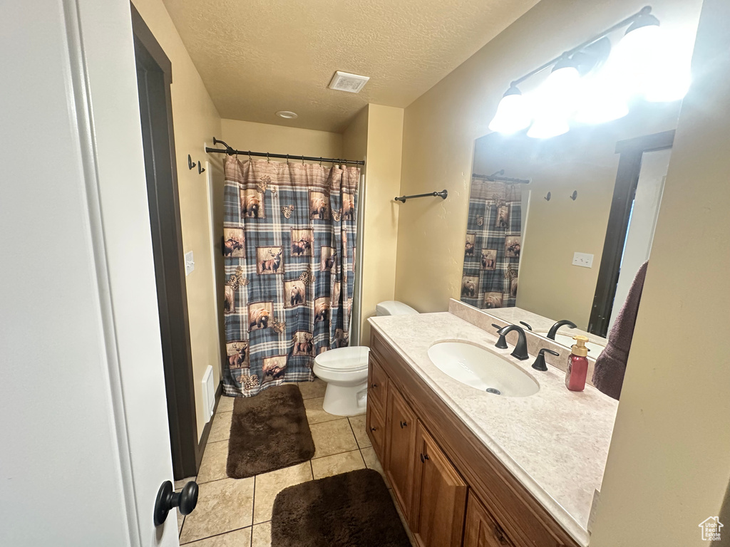 Full bathroom with vanity, a textured ceiling, toilet, tile patterned flooring, and a shower with shower curtain