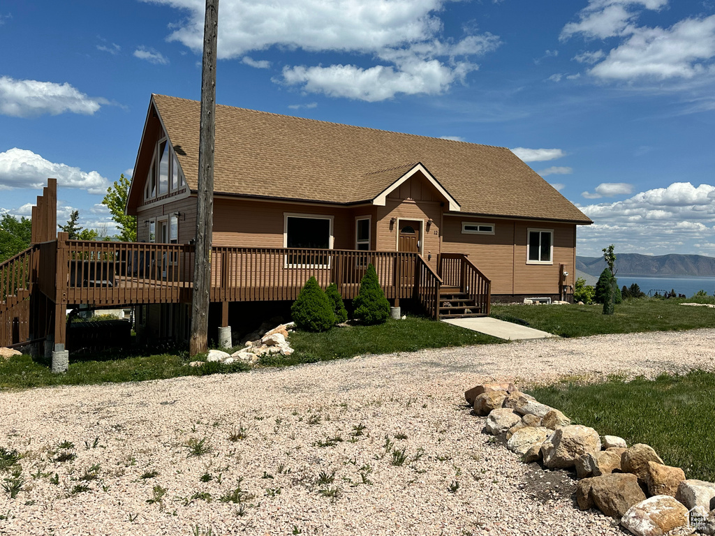 View of front facade featuring a deck with mountain view and roof with shingles