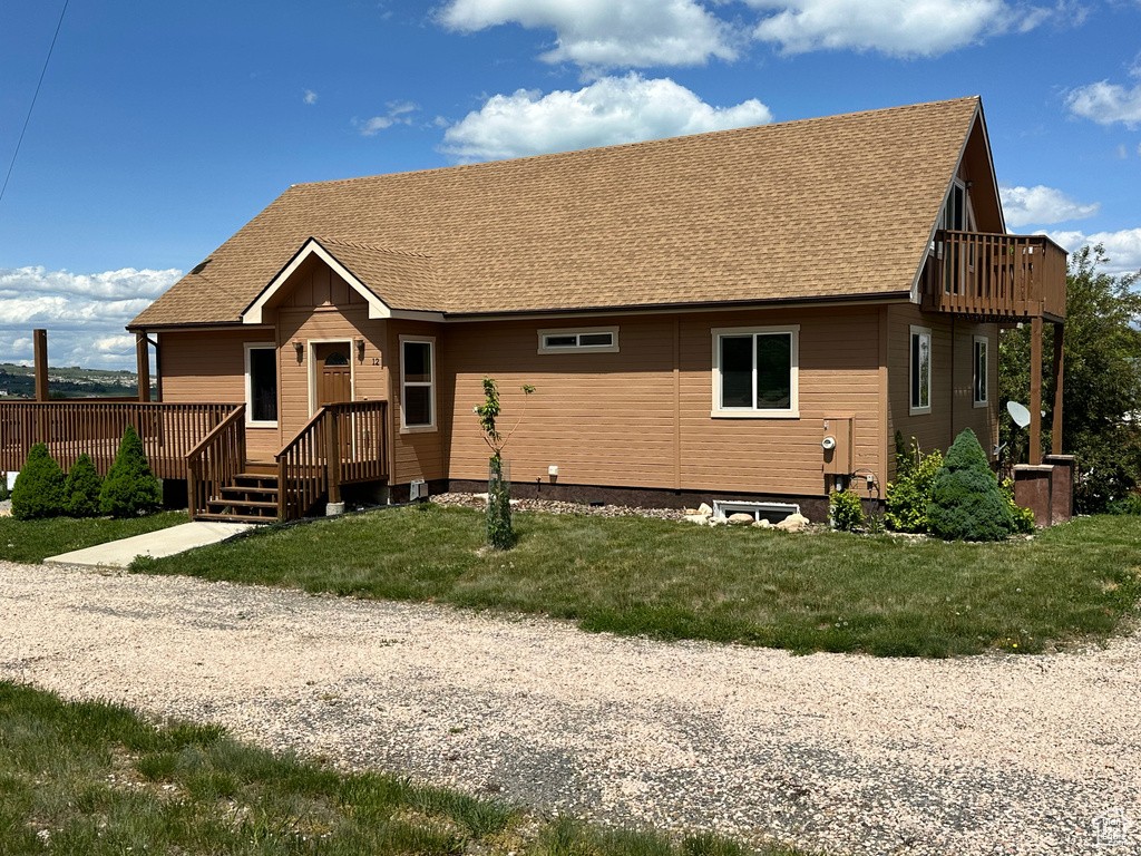 Rear view of house with a shingled roof, a lawn, and a wooden deck
