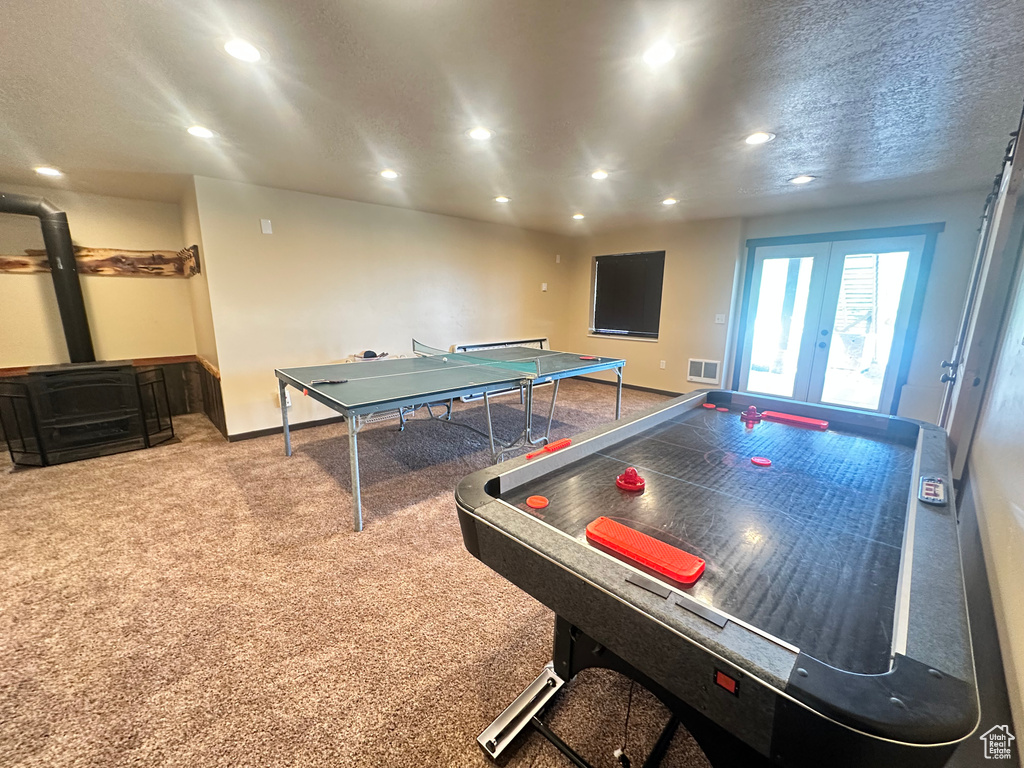 Playroom featuring recessed lighting, a wood stove, carpet flooring, baseboards, and french doors