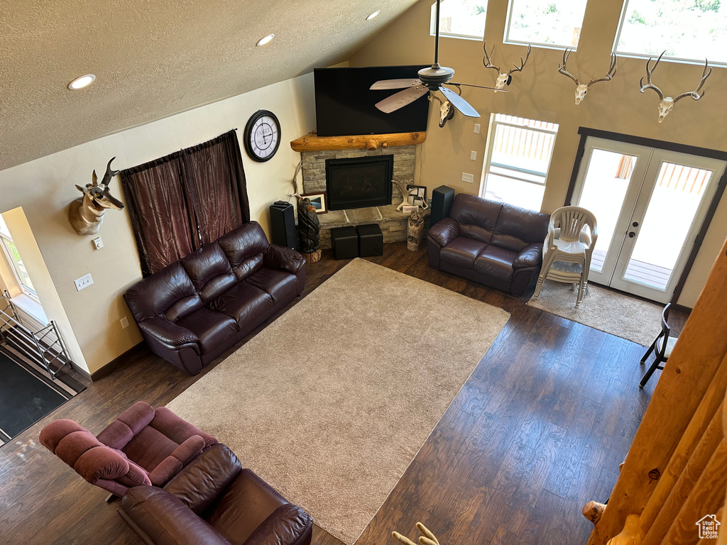 Living room with a fireplace, healthy amount of natural light, a ceiling fan, dark wood-style floors, and a textured ceiling