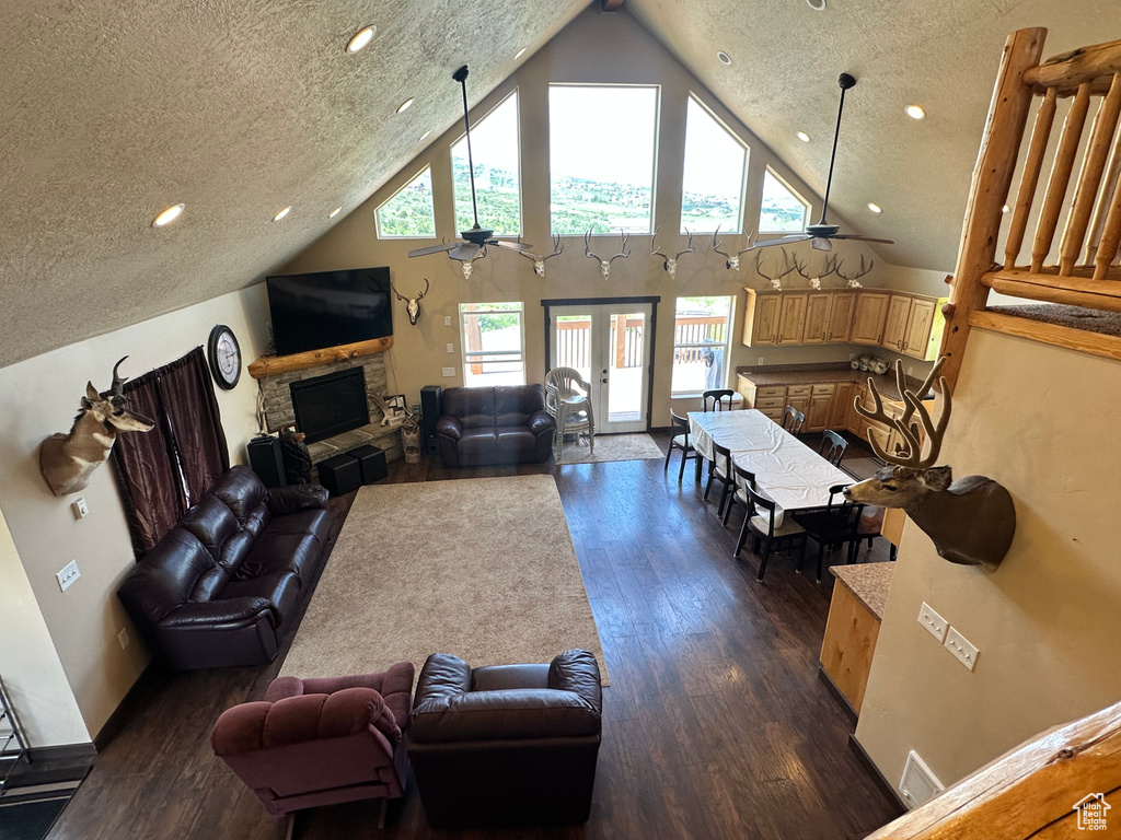 Living room featuring a ceiling fan, dark wood finished floors, a fireplace, high vaulted ceiling, and recessed lighting