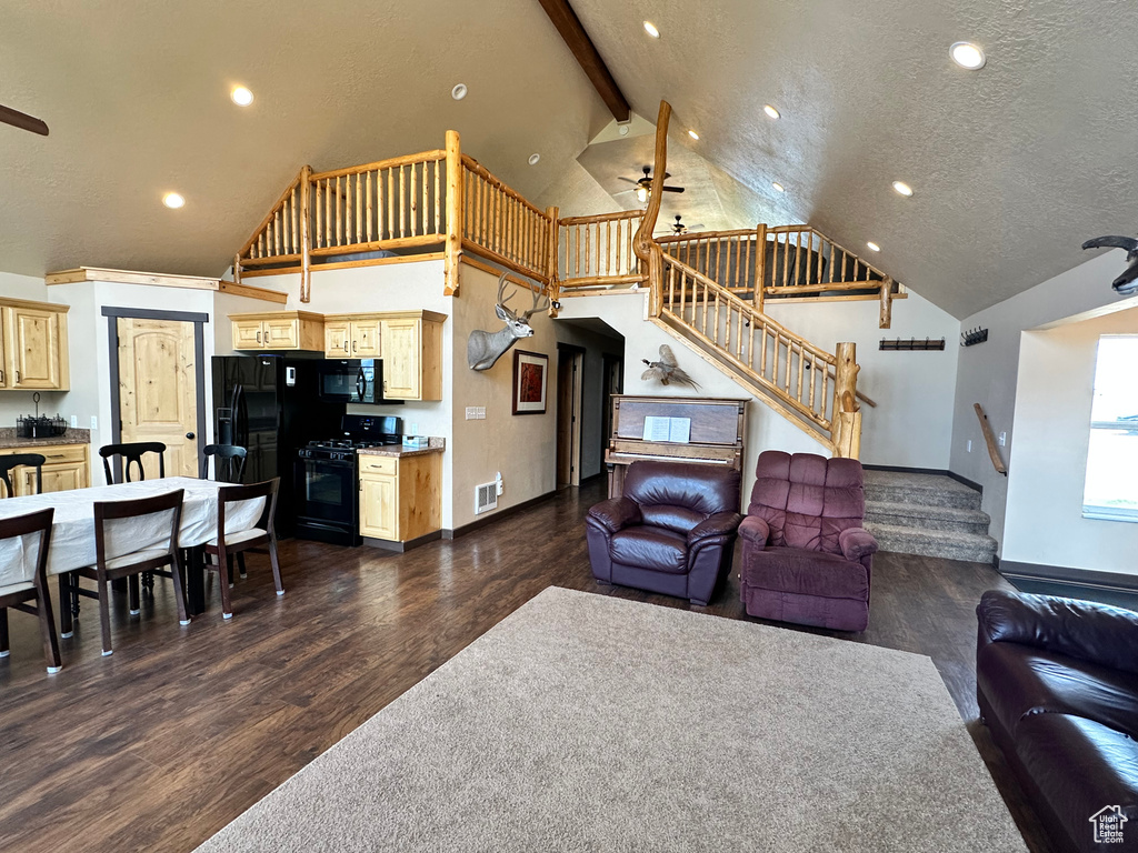 Living area with stairway, ceiling fan, dark wood finished floors, baseboards, and high vaulted ceiling