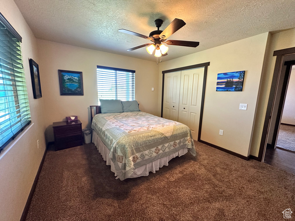 Bedroom featuring carpet flooring, a textured ceiling, a closet, ceiling fan, and baseboards