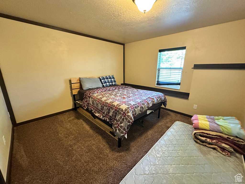 Carpeted bedroom featuring a textured ceiling and baseboards