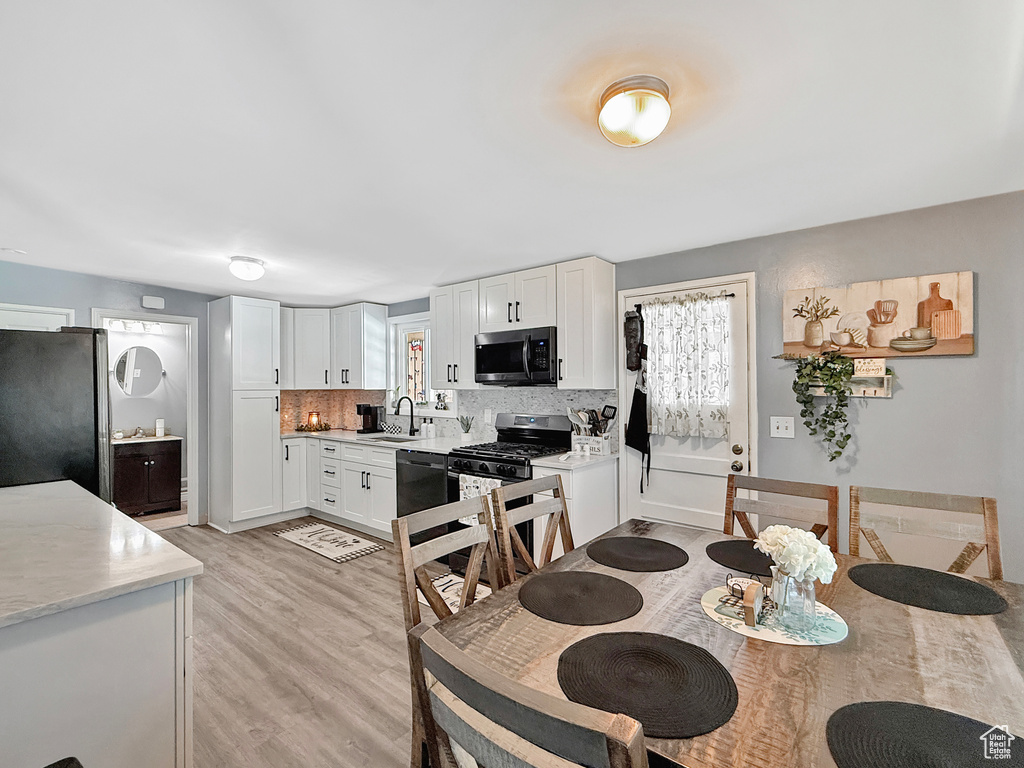 Kitchen featuring stainless steel appliances, a sink, light countertops, white cabinets, and tasteful backsplash