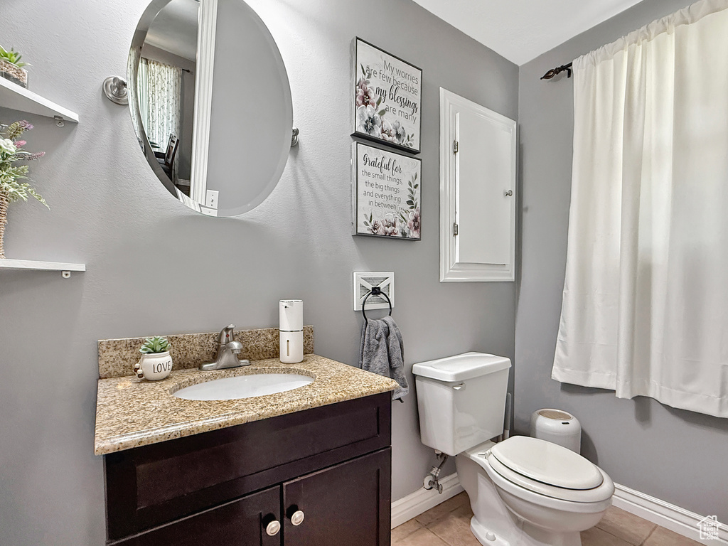 Bathroom featuring tile patterned flooring, toilet, baseboards, and vanity