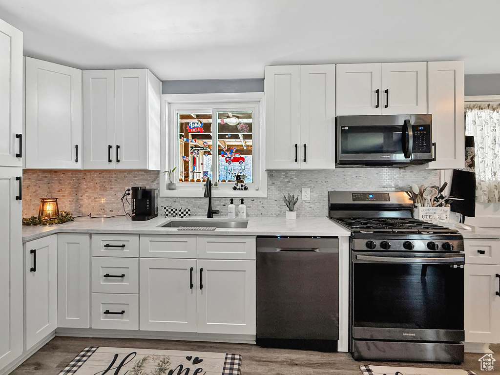 Kitchen with stainless steel appliances, a sink, healthy amount of natural light, and white cabinets
