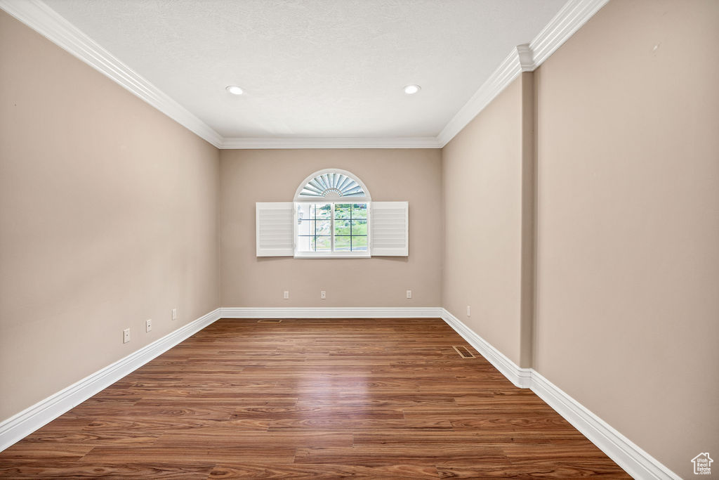 Unfurnished room with crown molding, baseboards, wood finished floors, and recessed lighting