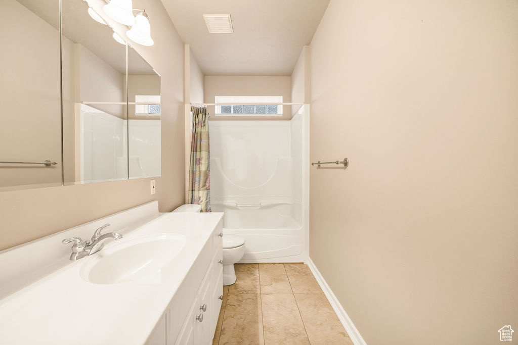 Full bathroom with vanity, toilet, tile patterned floors, shower / tub combo with curtain, and baseboards