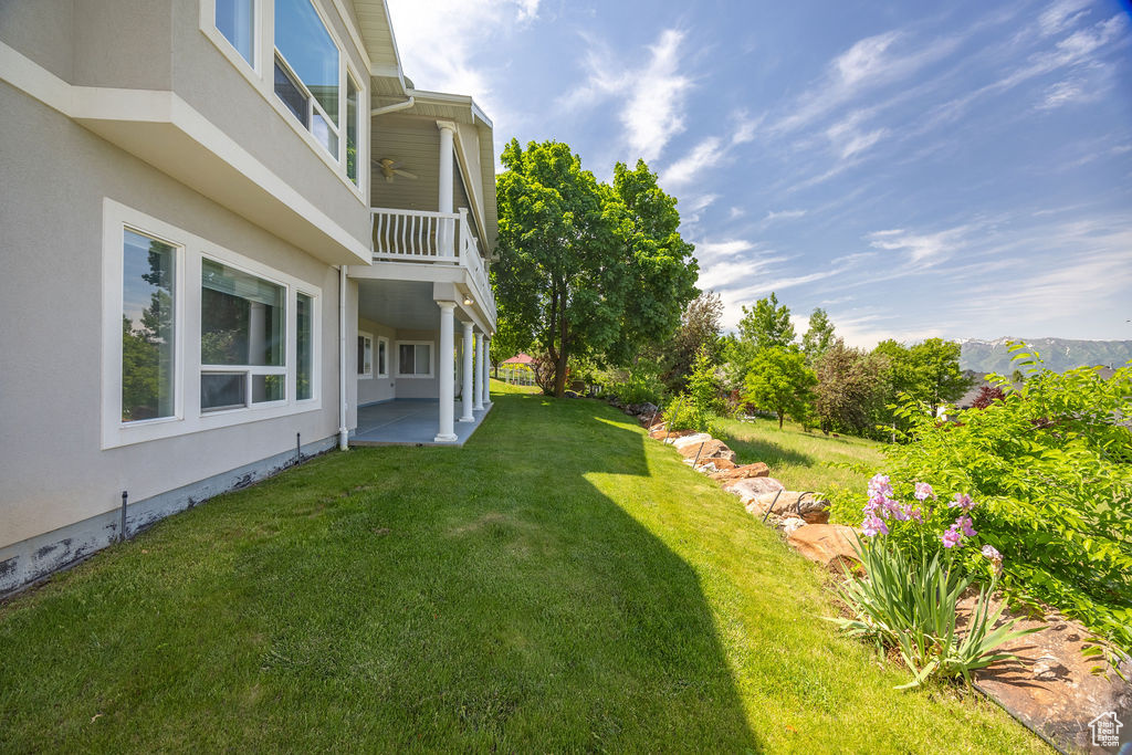 View of grassy yard featuring a patio area and a balcony