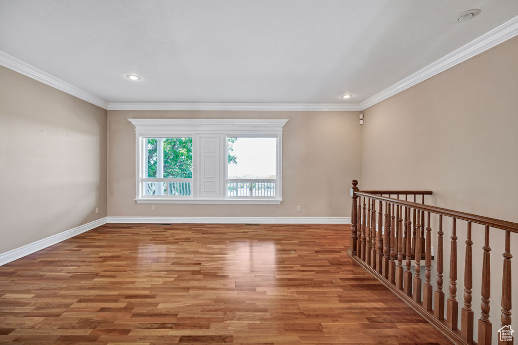 Empty room with light wood-type flooring, baseboards, crown molding, and recessed lighting