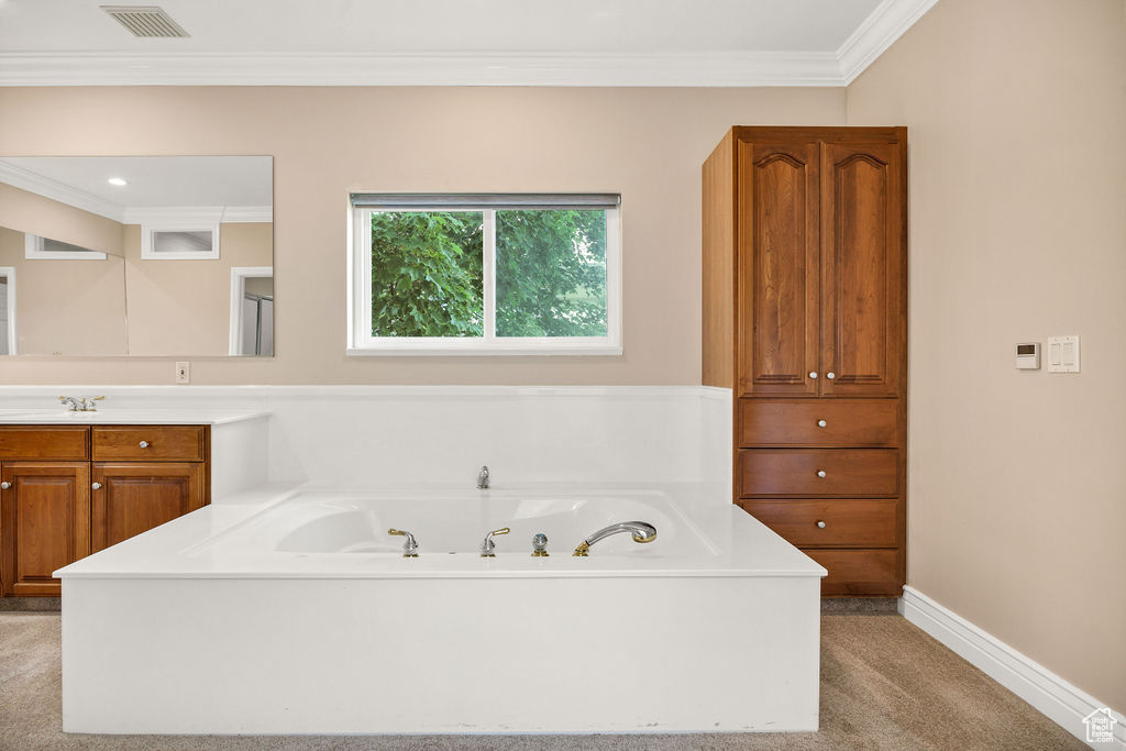 Bathroom with vanity, a jetted tub, crown molding, and baseboards