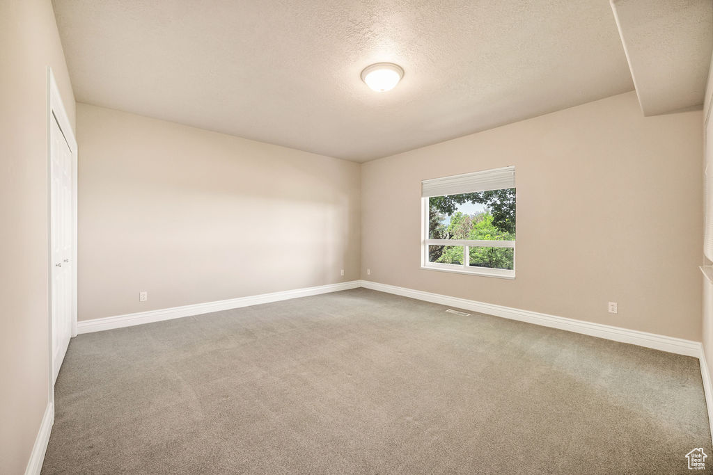Carpeted spare room with baseboards and a textured ceiling