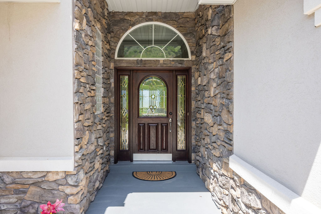 Property entrance with stone siding and stucco siding