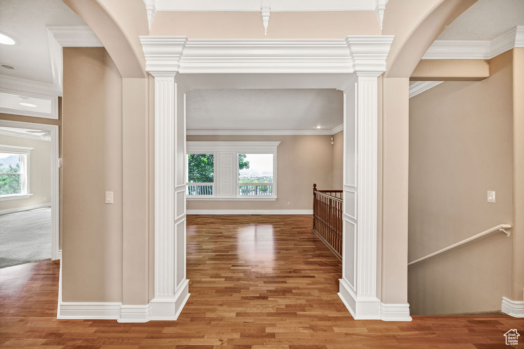 Hall featuring an upstairs landing, healthy amount of natural light, light wood finished floors, and ornamental molding