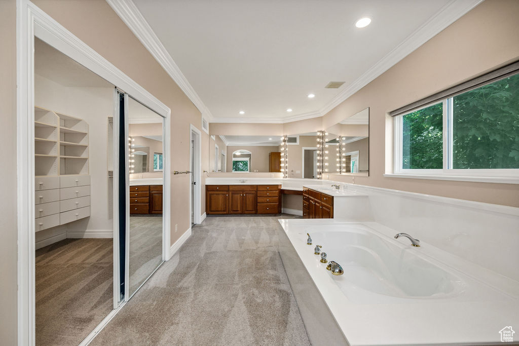 Bathroom featuring vanity, a bath, ornamental molding, and recessed lighting