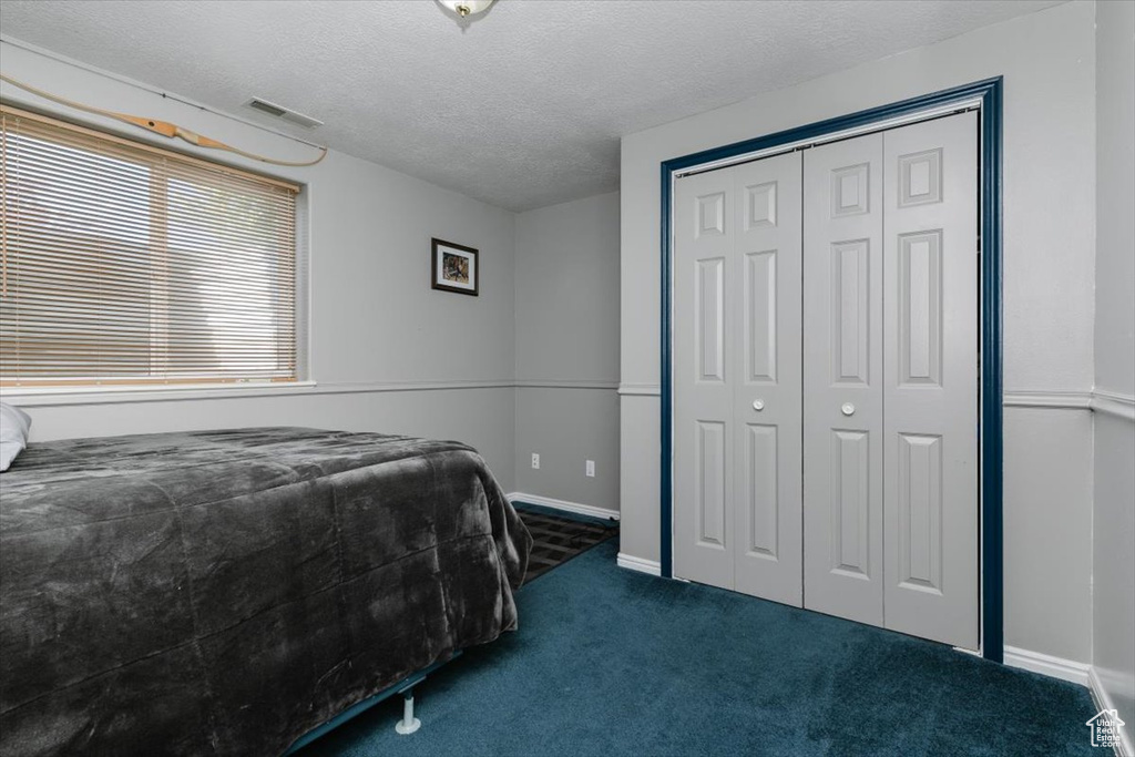 Bedroom with carpet, a closet, a textured ceiling, and baseboards