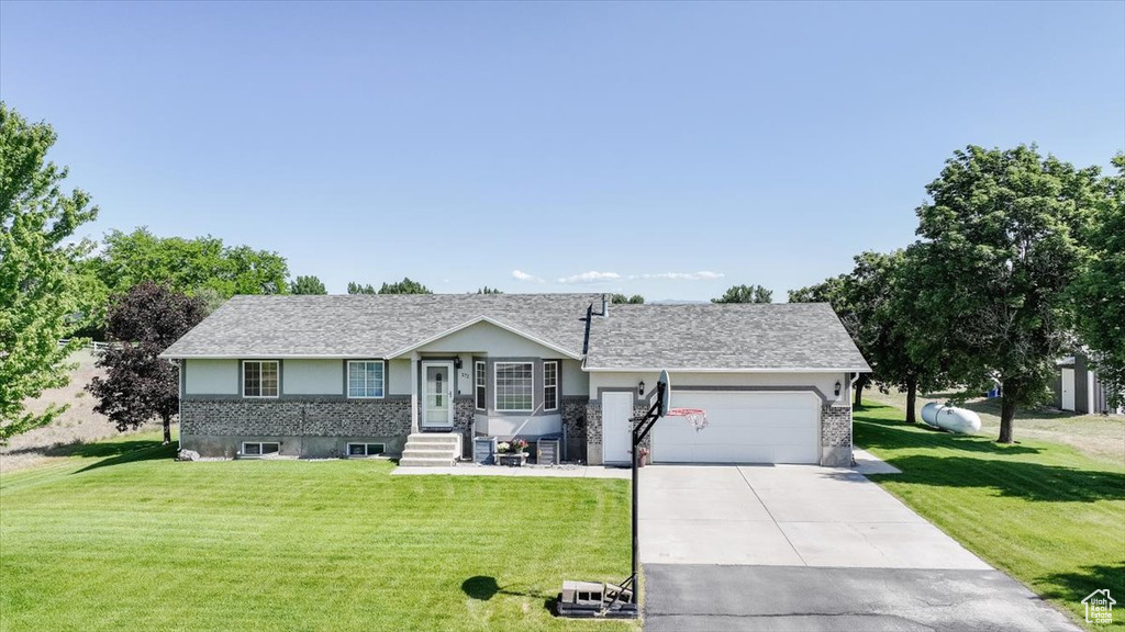 Ranch-style house with a garage, concrete driveway, and a front lawn