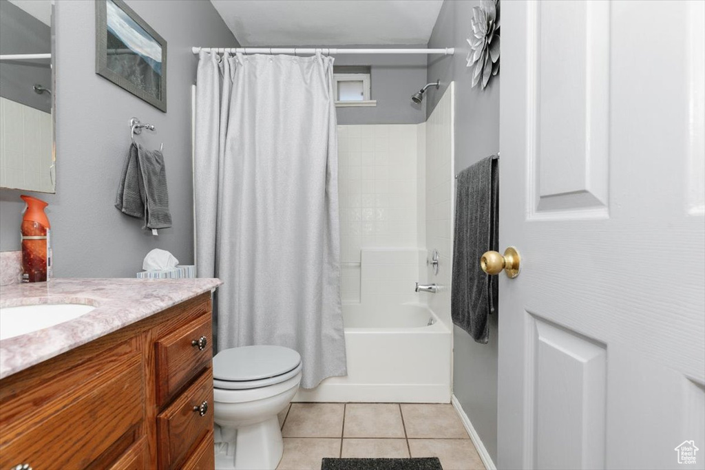Bathroom with vanity, toilet, shower / bathtub combination with curtain, and tile patterned flooring
