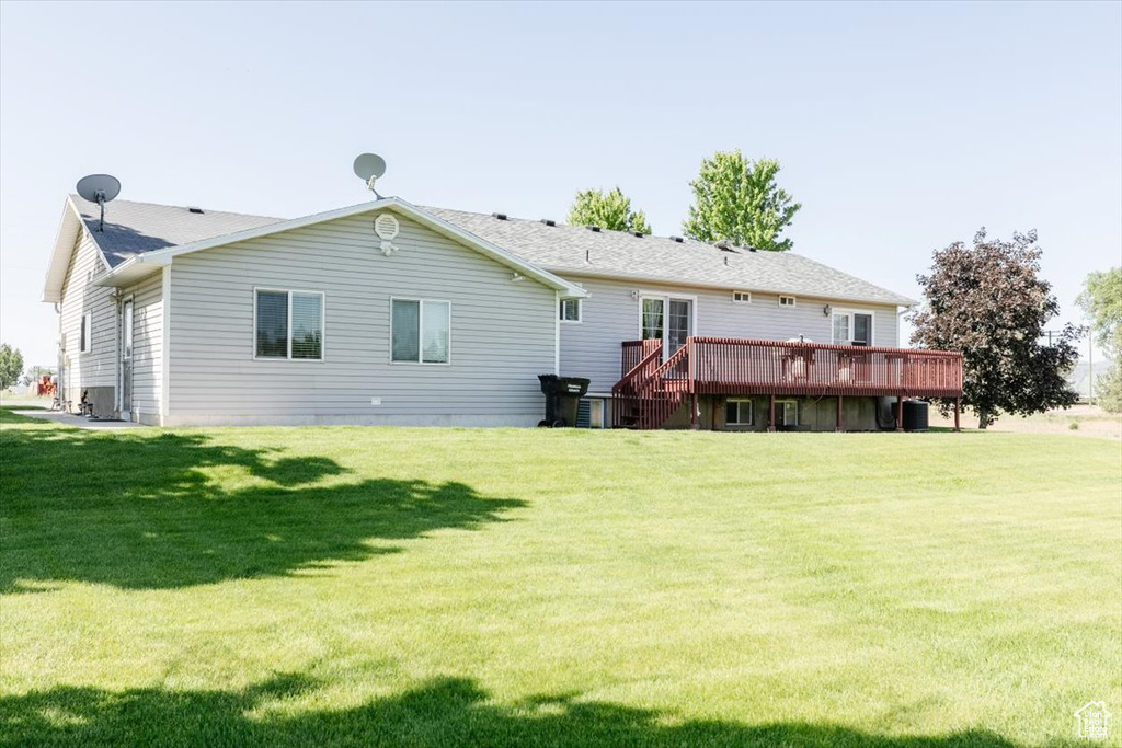 Rear view of house with a wooden deck and a yard