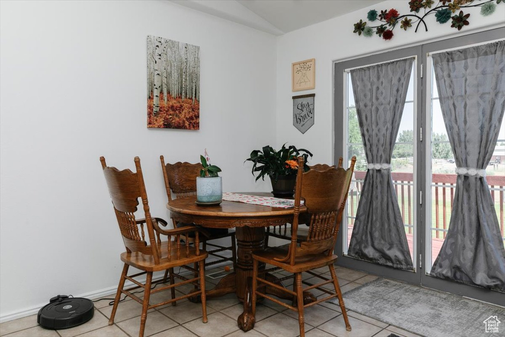 Dining room featuring light tile patterned floors, vaulted ceiling, and baseboards