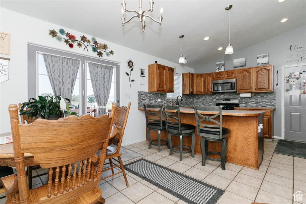 Dining space featuring a chandelier, lofted ceiling, light tile patterned floors, and recessed lighting