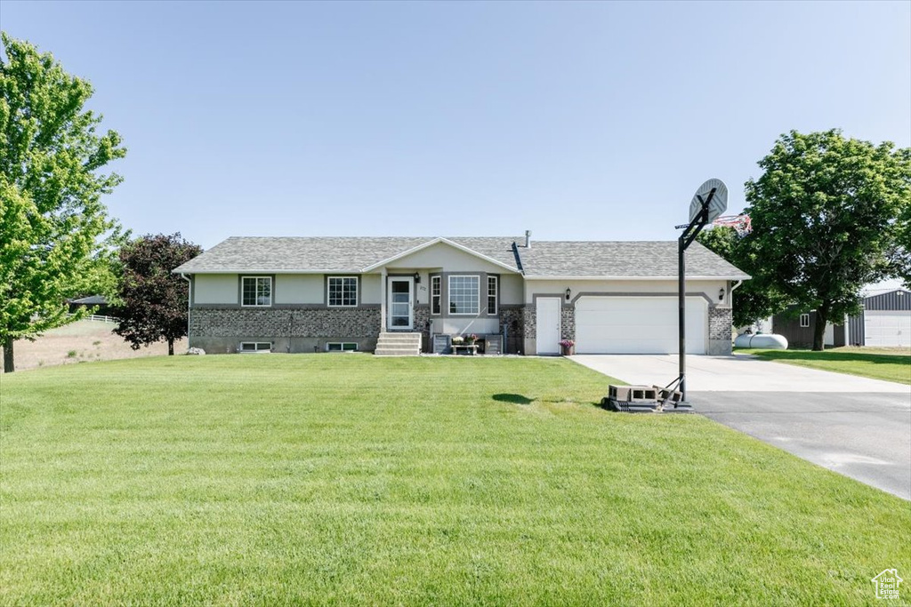 Single story home featuring concrete driveway, a garage, and a front lawn