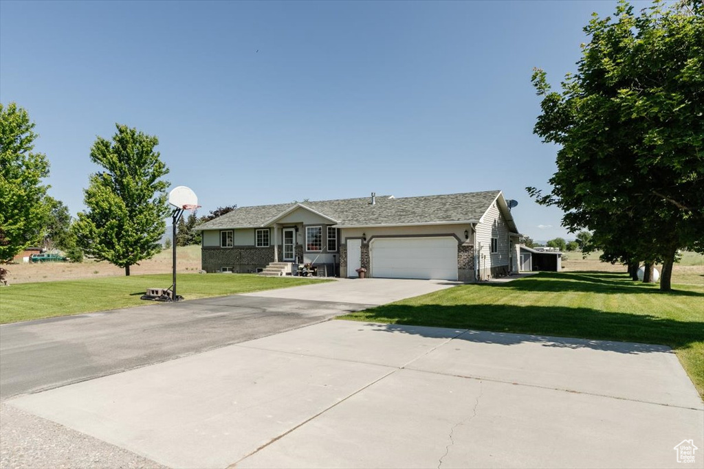 Ranch-style house featuring a garage, a front yard, and concrete driveway