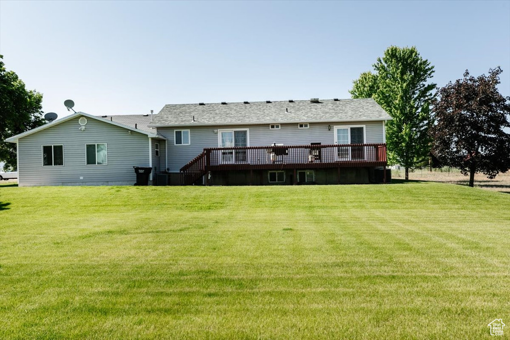 Back of house with a deck and a lawn