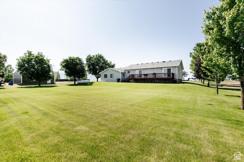 View of grassy yard with a wooden deck