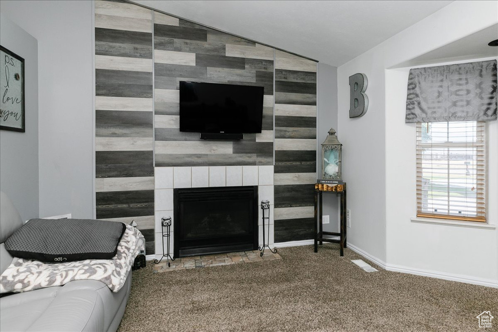 Living room featuring an accent wall, carpet, lofted ceiling, a fireplace, and baseboards