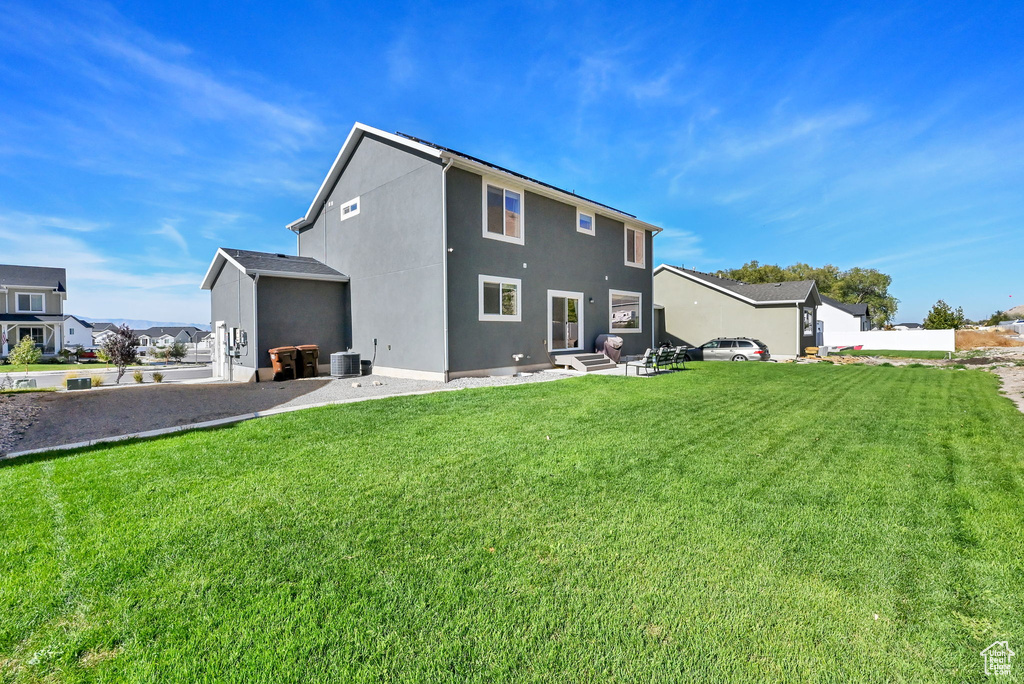 Back of house featuring a yard, stucco siding, and central air condition unit